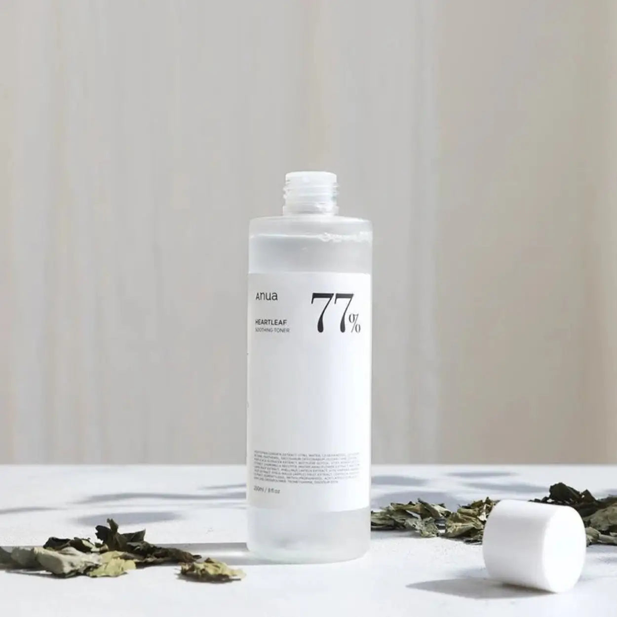 Frasco do ANUA Heartleaf 77% Soothing Toner junto a acessórios de skincare – tónico facial suave com heartleaf para reduzir vermelhidão e hidratar profundamente, cosmética coreana, skincare k-beauty Portugal