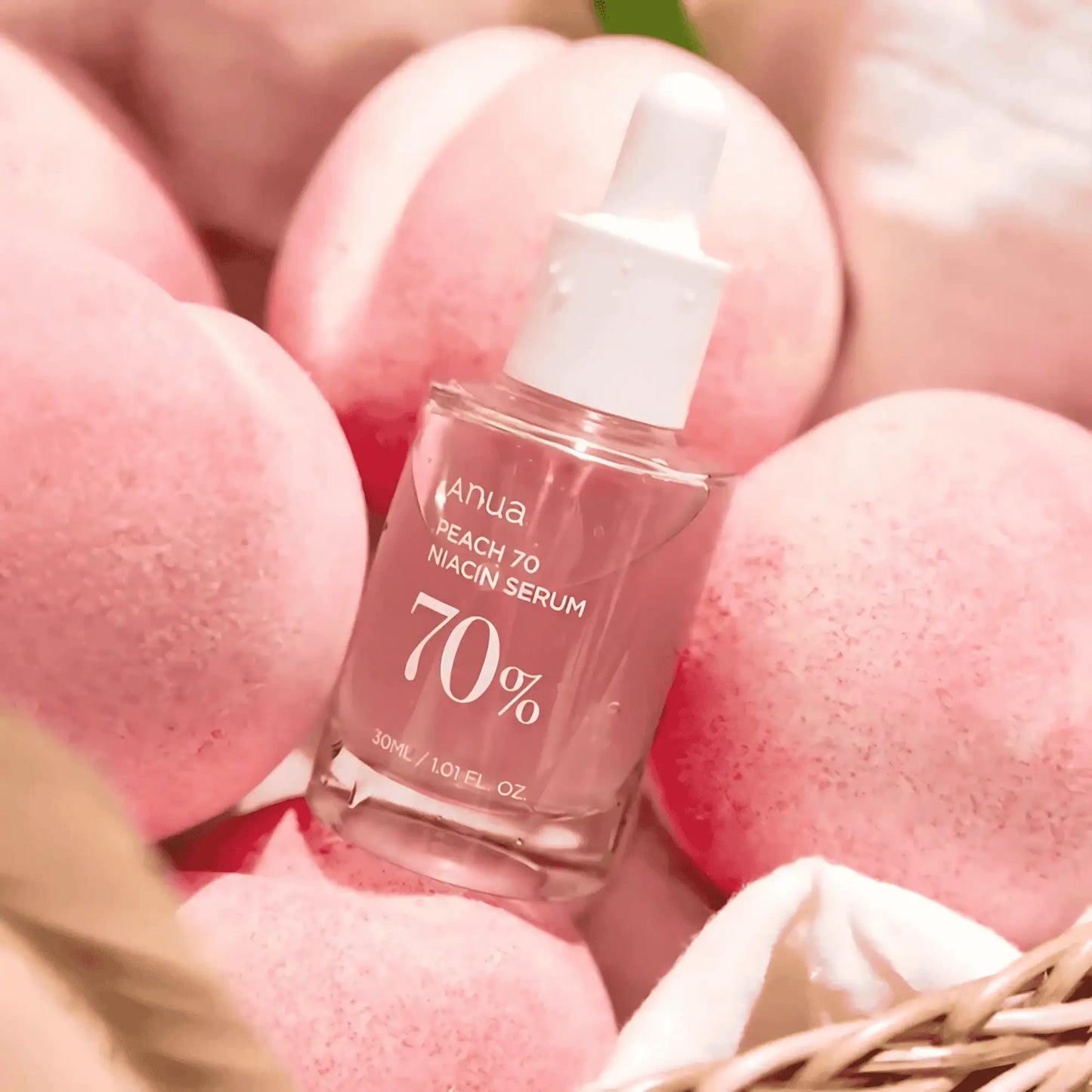 ANUA Peach 70% Niacinamide Serum num cesto rodeado por frascos e pêssegos – sérum antioxidante e uniformizante com textura leve, cosmética coreana, skincare k-beauty Portugal