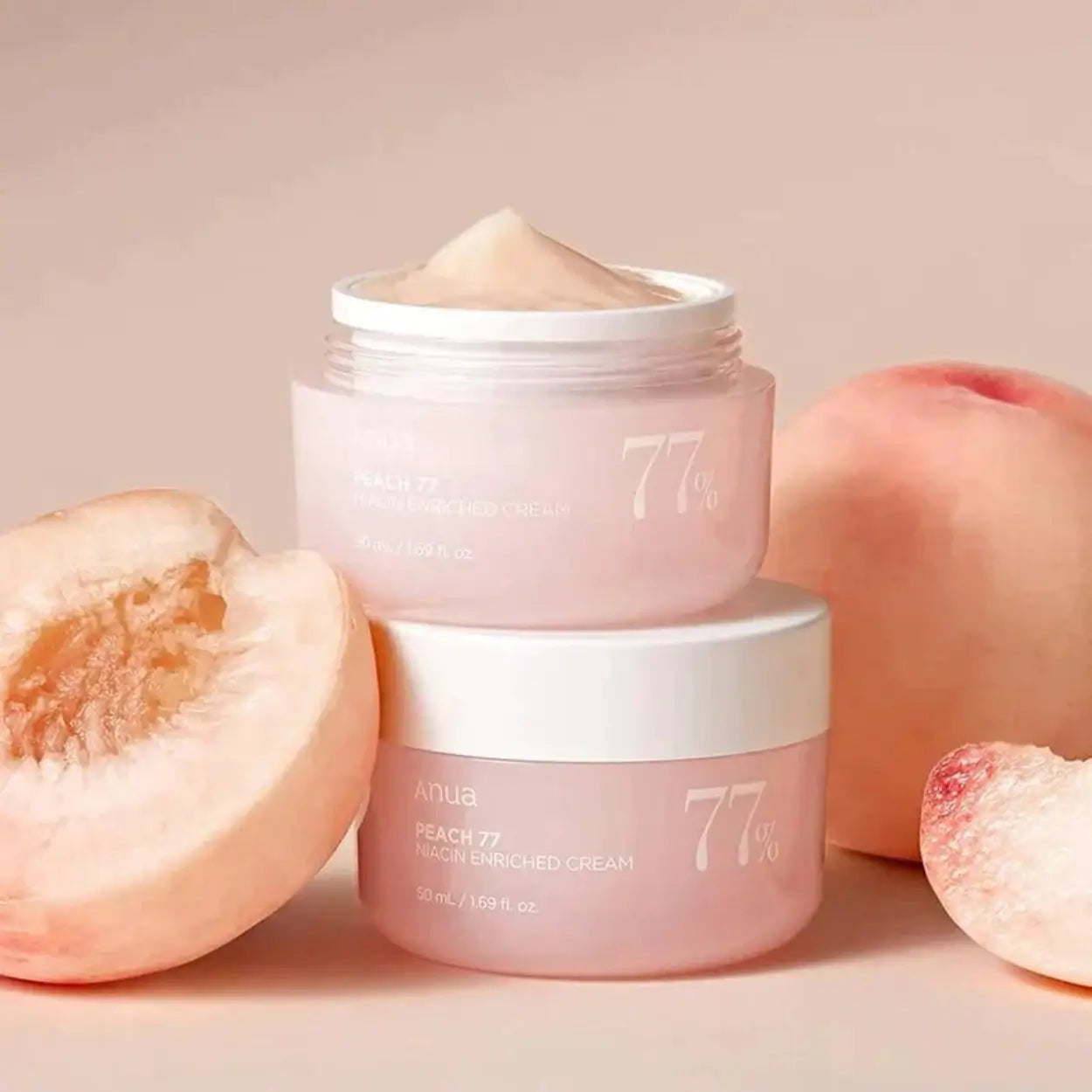 ANUA Peach 77% Niacin Enriched Cream empilhado ao lado de pêssegos cortados – cuidado hidratante de uso diário para uniformizar o tom da pele, cosmética coreana, skincare k-beauty Portugal