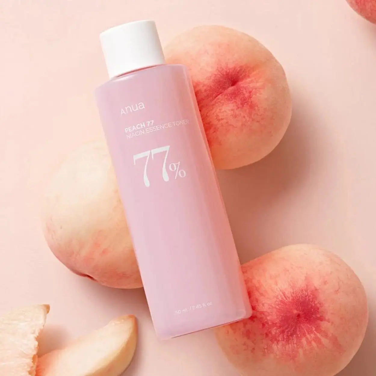 ANUA Peach 77% Niacin Essence Toner deitado junto a pêssegos – essência tónica coreana com niacinamida para clarear manchas e revitalizar a pele, cosmética coreana, skincare k-beauty Portugal