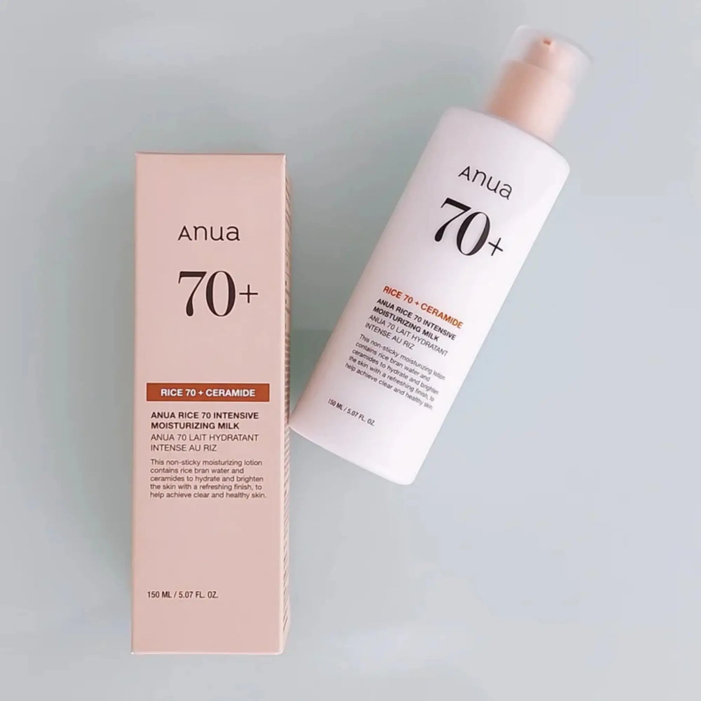 Anua Rice 70 Intensive Moisturizing Milk 150ml, loção facial coreana hidratante com arroz para suavizar textura e dar luminosidade, frasco ao lado da embalagem original sobre fundo cinzento claro, cosmética coreana skincare k-beauty Portugal.