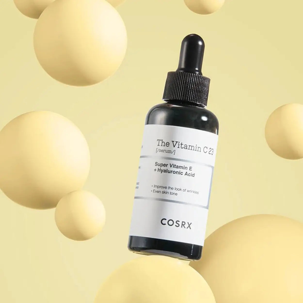 Frasco do COSRX The Vitamin C 23 Serum sobre fundo amarelo com esferas – sérum iluminador coreano com fórmula concentrada, ideal para pele baça, cosmética coreana, skincare k-beauty Portugal