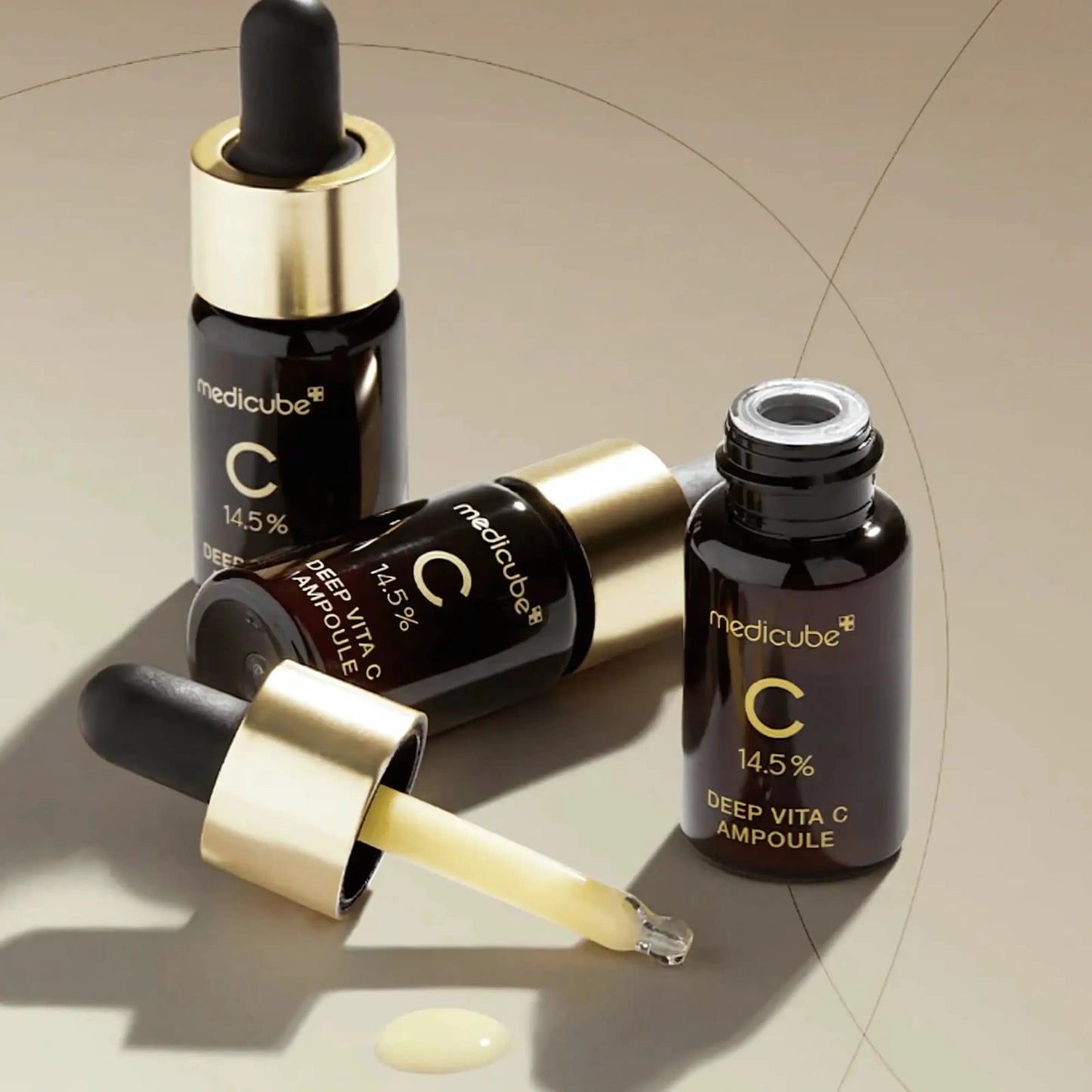 Medicube Deep Vita C Ampoule 2.0 – dois frascos sobre fundo bege com reflexo dourado, reforçando a ação antioxidante e iluminadora desta ampola coreana de alta eficácia