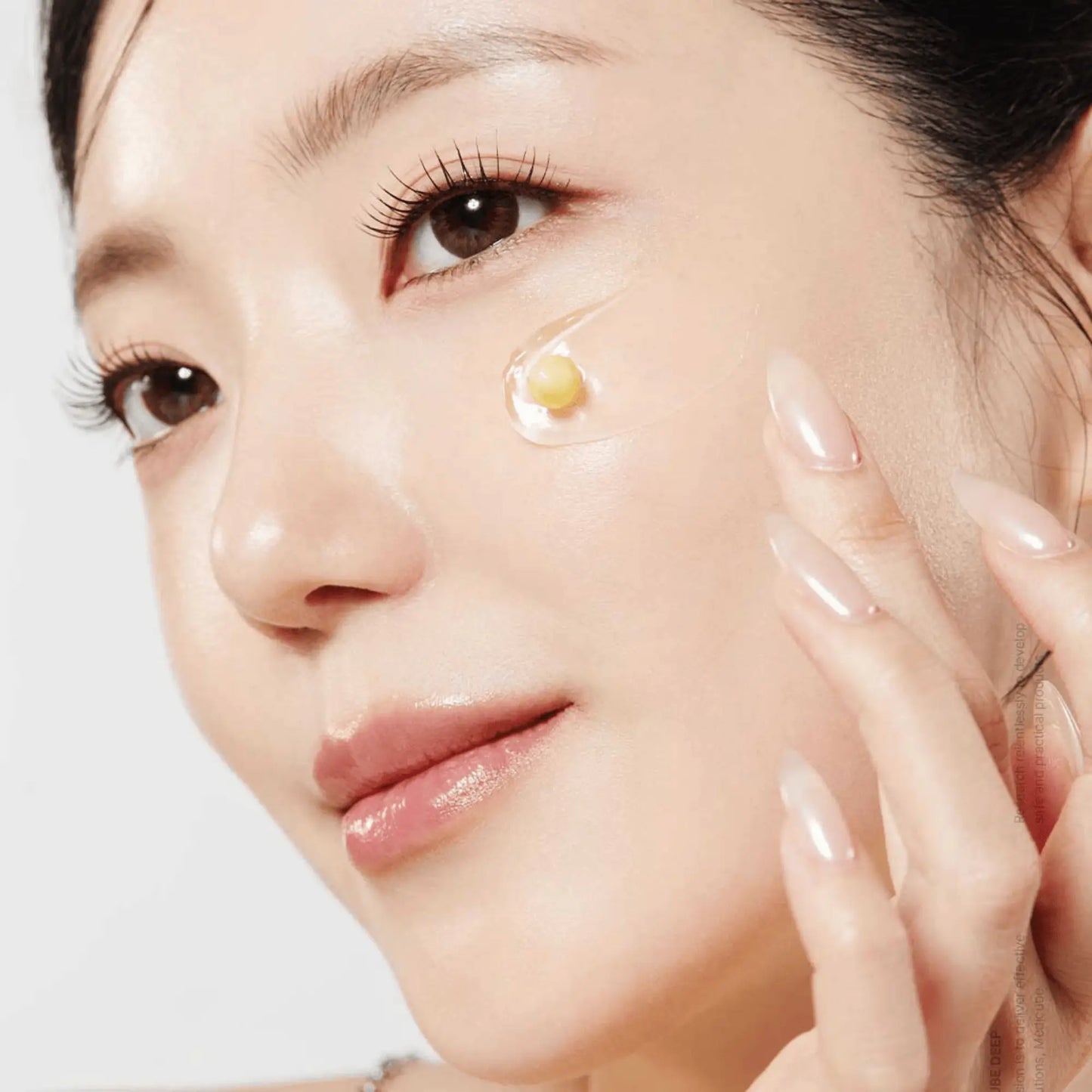 Medicube Deep Vita C Capsule Cream 55g, creme facial coreano iluminador com vitamina C encapsulada que uniformiza o tom e reduz manchas, modelo feminina a aplicar pontos de creme na face, fundo branco, cosmética coreana skincare k-beauty Portugal.