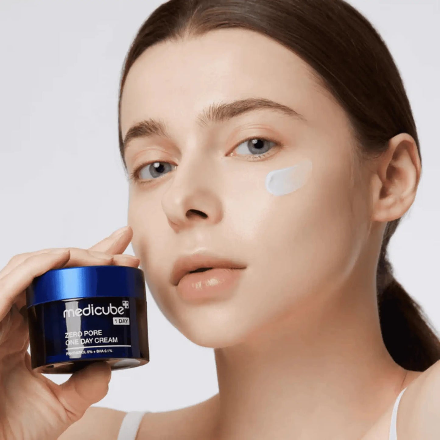 Medicube Zero Pore One Day Cream 50ml, creme facial coreano com niacinamida e adenosina para hidratação e suavização de poros, modelo feminina segura o frasco junto ao rosto, fundo branco, cosmética coreana skincare k-beauty Portugal.