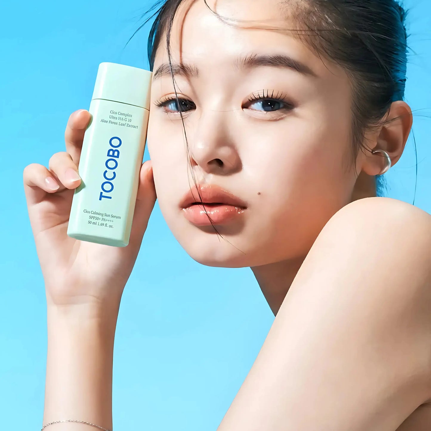 TOCOBO Cica Calming Sun Serum – modelo coreana a aplicar o protetor solar com expressão serena, demonstrando a absorção rápida e acabamento invisível, ideal para pele sensibilizada