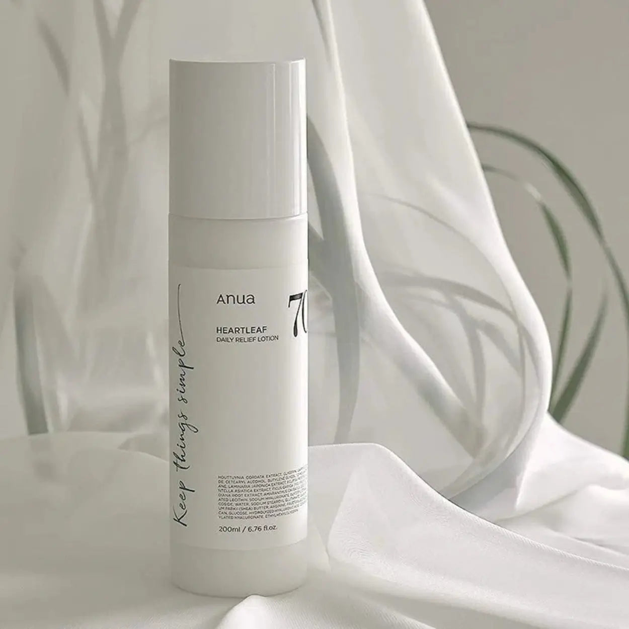 ANUA Heartleaf 70% Daily Relief Lotion sobre tecido branco suave – loção coreana calmante com 70% de heartleaf para hidratar e acalmar a pele sensível, cosmética coreana, skincare k-beauty Portugal