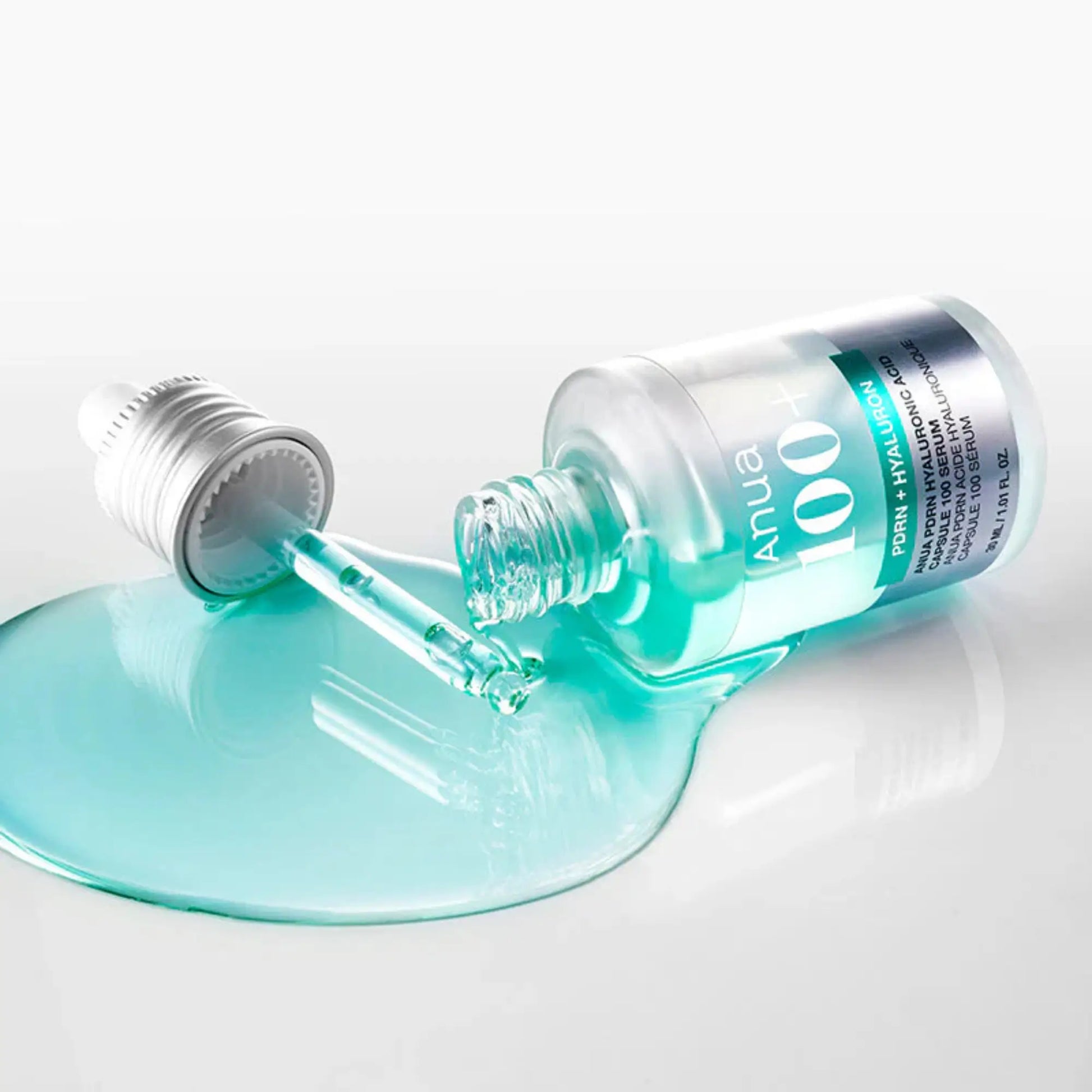 Anua PDRN Hyaluronic Acid Capsule 100 Serum 30ml, sérum coreano hidratante com ácido hialurónico encapsulado e PDRN, favorece regeneração e firmeza, frasco deitado com líquido azul turquesa a escorrer sobre fundo branco, cosmética coreana skincare k-beauty Portugal.