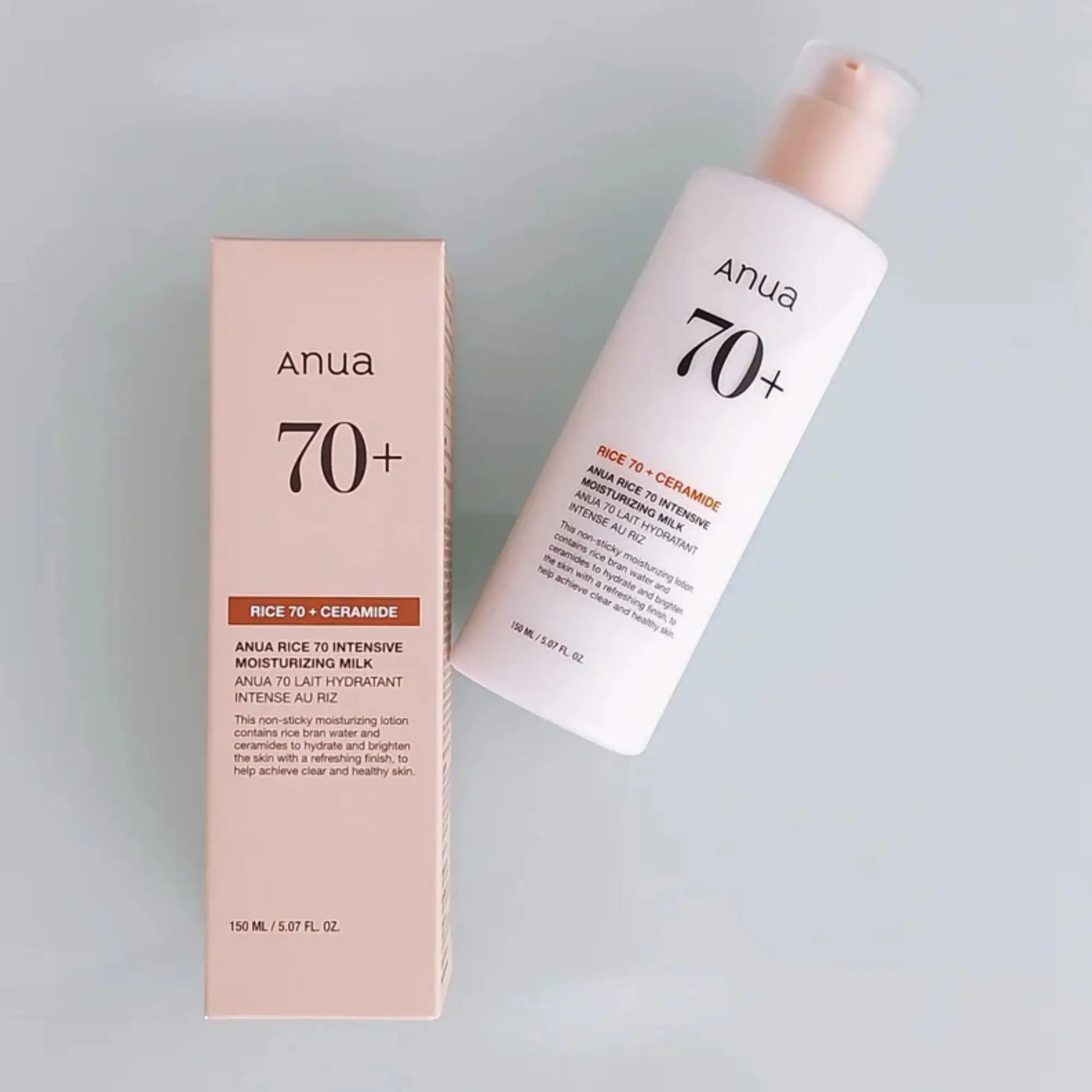 Anua Rice 70 Intensive Moisturizing Milk 150ml, loção facial coreana hidratante com arroz para suavizar textura e dar luminosidade, frasco ao lado da embalagem original sobre fundo cinzento claro, cosmética coreana skincare k-beauty Portugal.