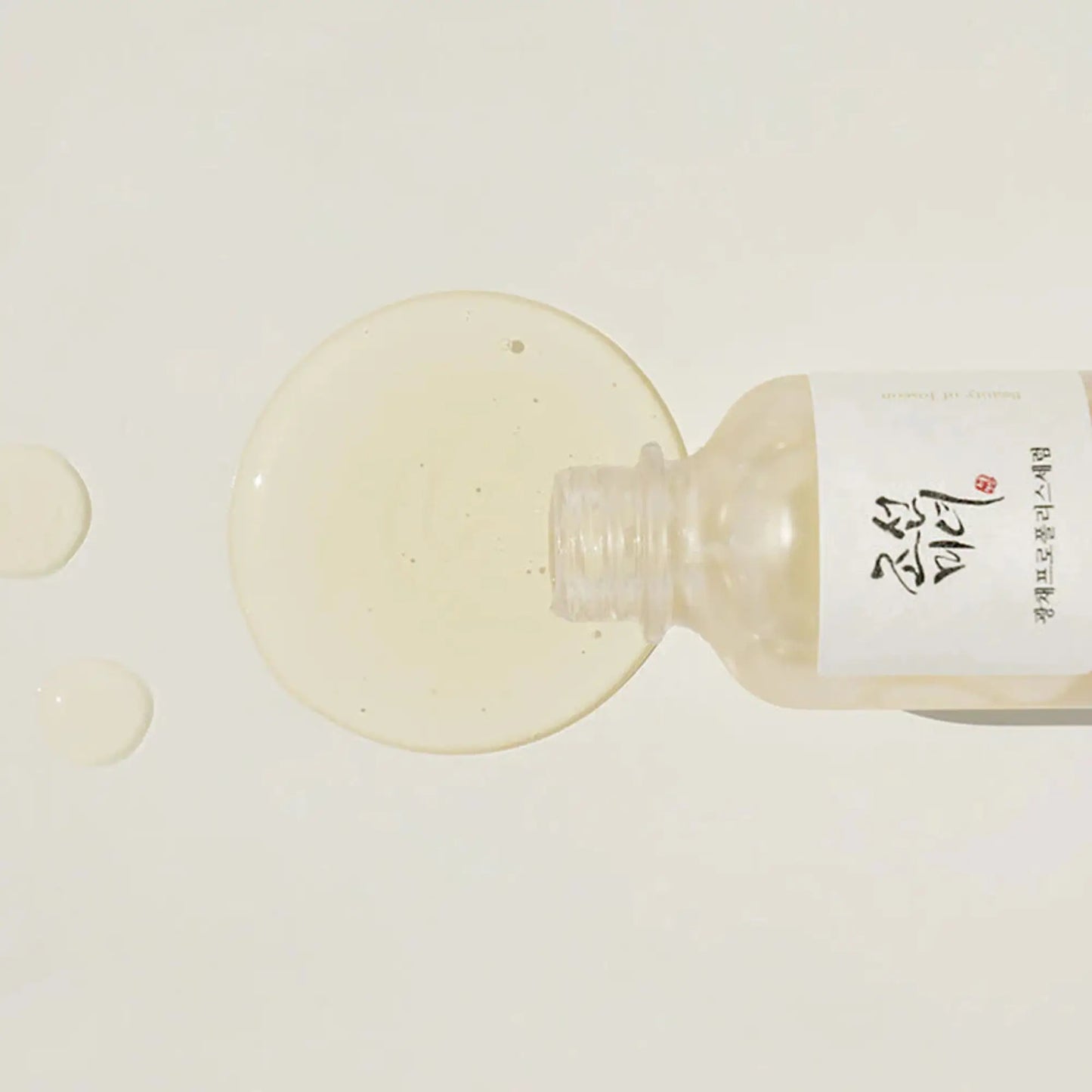 Beauty of Joseon Glow Serum Propolis + Niacinamide 30ml, sérum facial coreano iluminador que reduz imperfeições, hidrata e dá luminosidade, frasco deitado com conta-gotas e líquido dourado espalhado sobre fundo branco, cosmética coreana skincare k-beauty Portugal.