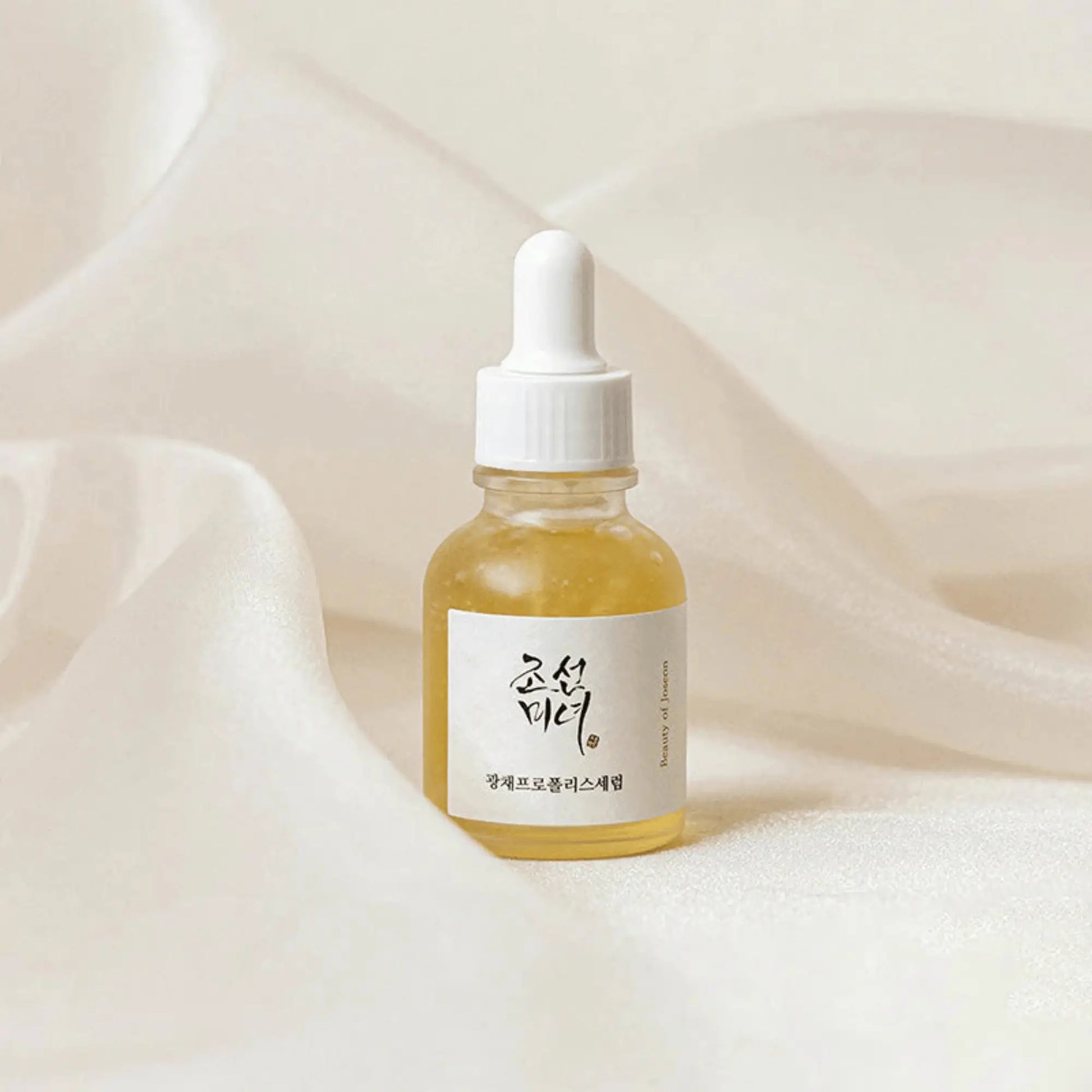 Beauty of Joseon Glow Serum Propolis + Niacinamide 30ml, sérum coreano iluminador com própolis calmante e niacinamida para luminosidade, uniformização do tom e redução de poros, frasco em pé sobre tecido branco suave, cosmética coreana skincare k-beauty Portugal.