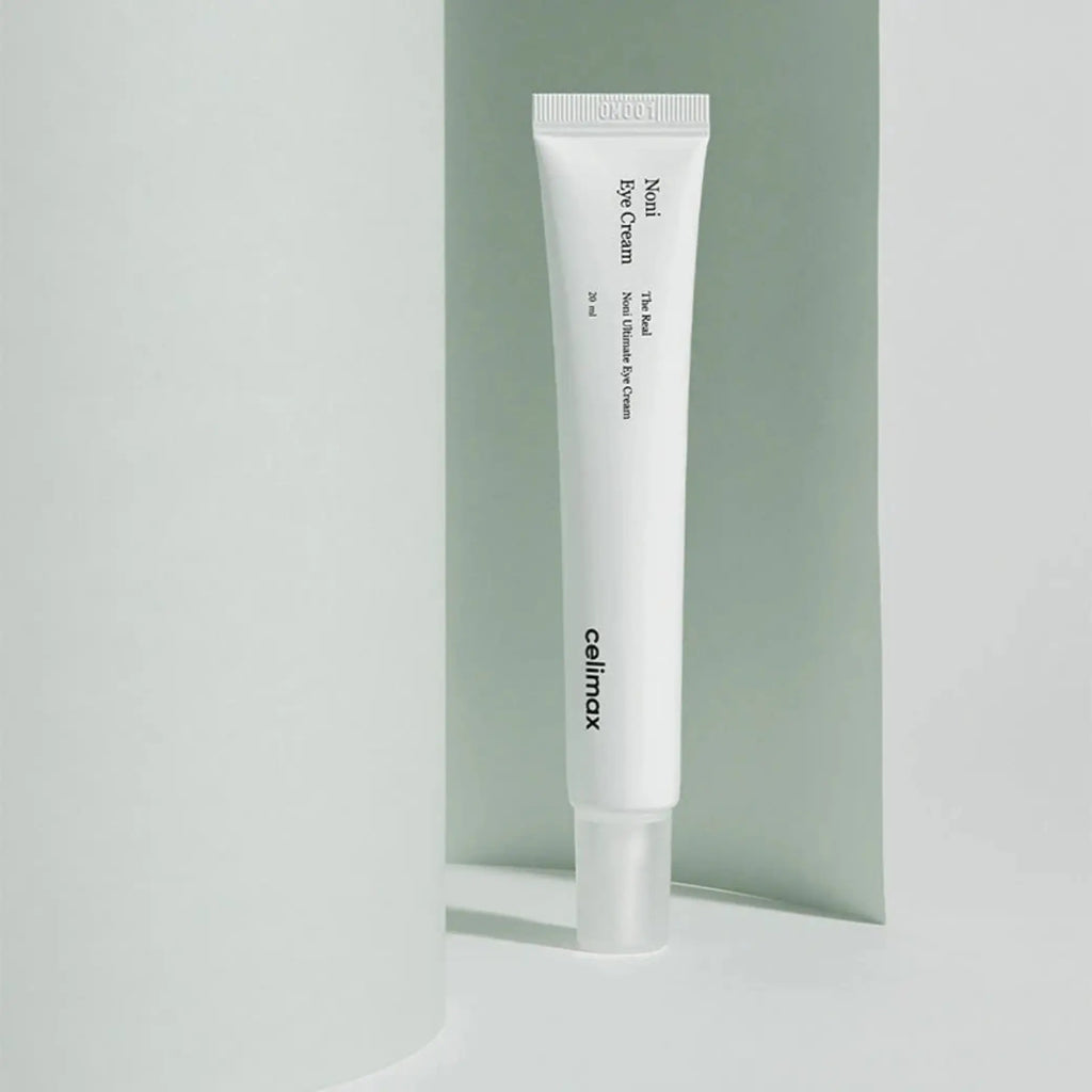 The Real Noni Ultimate Eye Cream da Celimax em tubo em pé com fundo verde claro