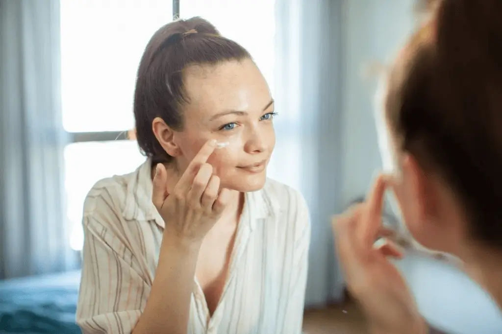 Mulher a aplicar creme de olhos com os dedos — cuidado específico da cosmética coreana para a zona sensível do contorno ocular. Ideal para prevenir rugas, reduzir olheiras e hidratar. Skincare coreano para rosto delicado – skincare k-beauty Portugal.