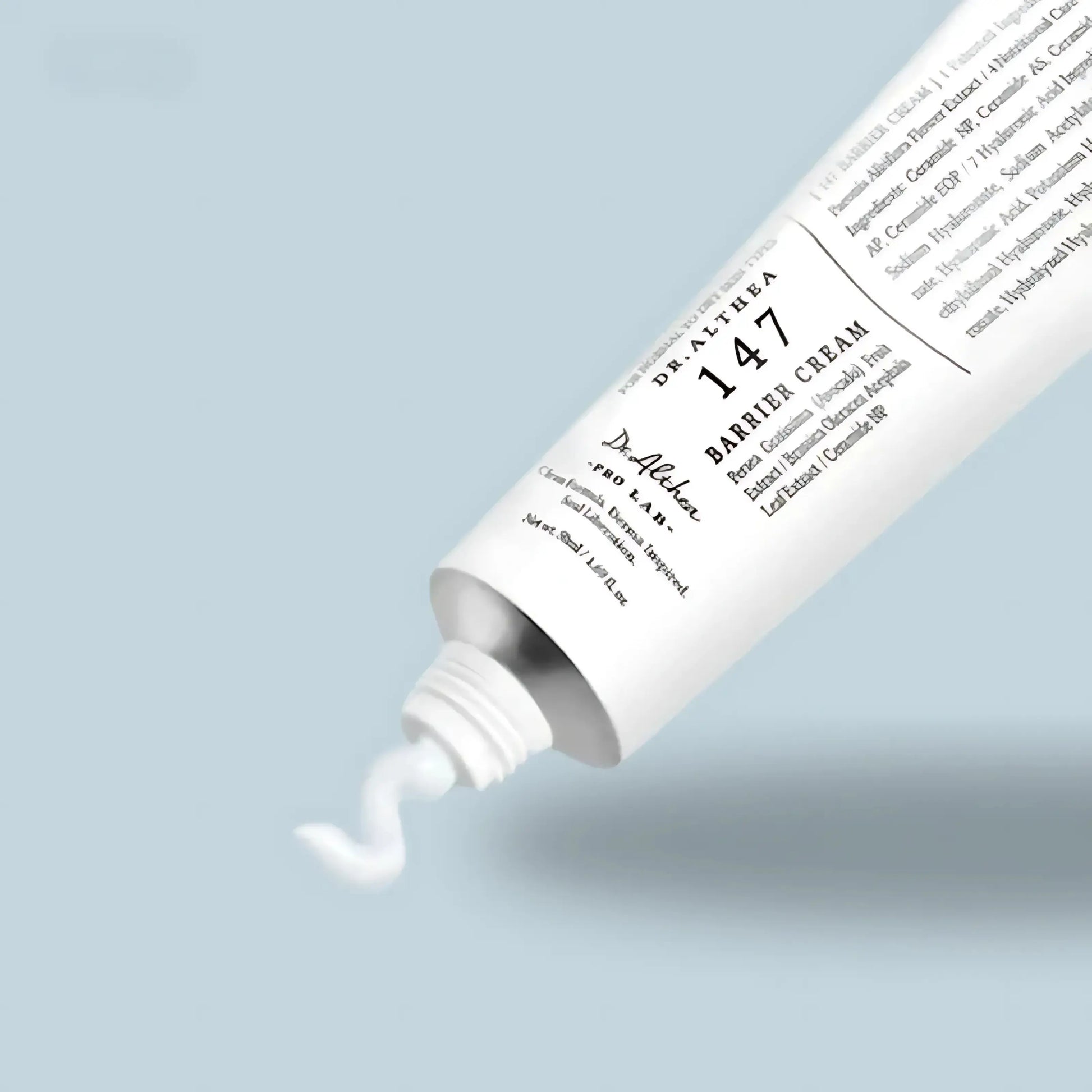 Dr. Althea 147 Barrier Cream – textura do creme a ser espremida do tubo num fundo azul claro, destacando a leveza e ação protetora, ideal para pele seca ou sensível