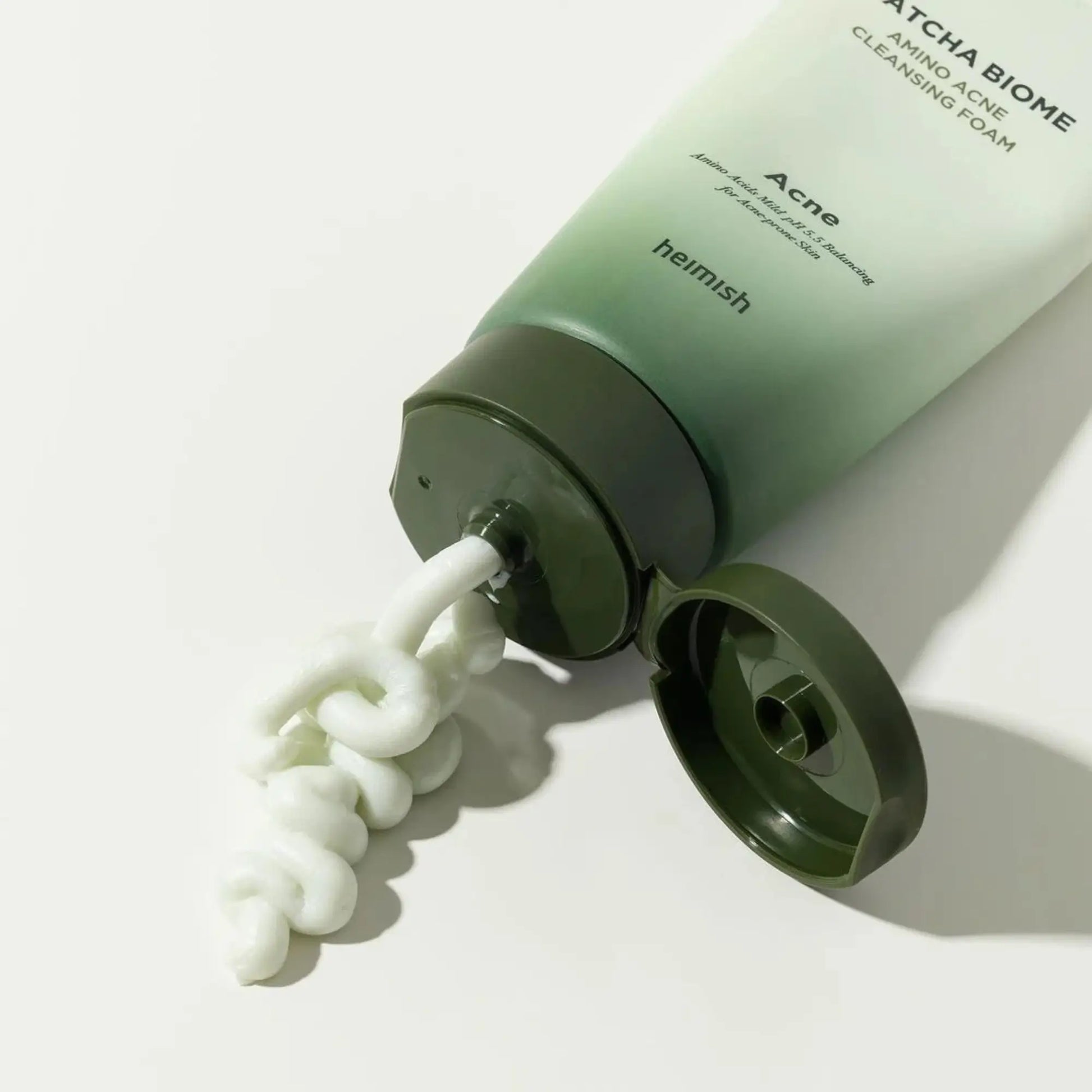 Heimish Matcha Biome Amino Acne Cleansing Foam 150g, espuma de limpeza facial coreana com aminoácidos e matcha que suavizam e purificam, close-up do tubo aberto a dispensar textura branca cremosa, cosmética coreana skincare k-beauty Portugal.