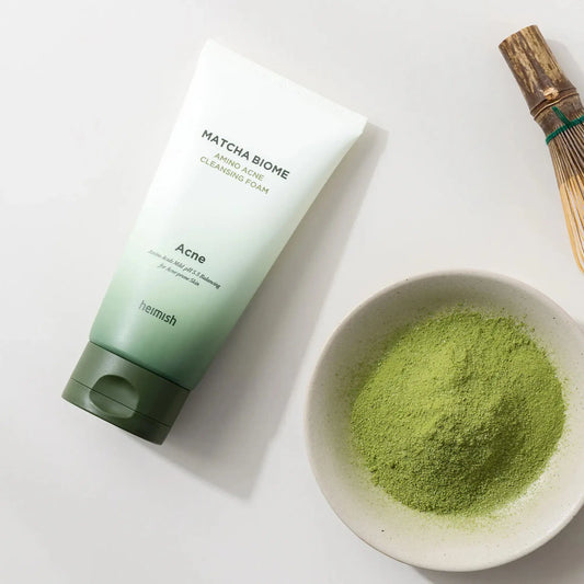 Heimish Matcha Biome Amino Acne Cleansing Foam 150g, espuma de limpeza facial coreana com matcha e aminoácidos que purificam poros, controlam oleosidade e acalmam pele sensível, frasco em pé com pó de matcha ao lado sobre fundo branco, cosmética coreana skincare k-beauty Portugal.
