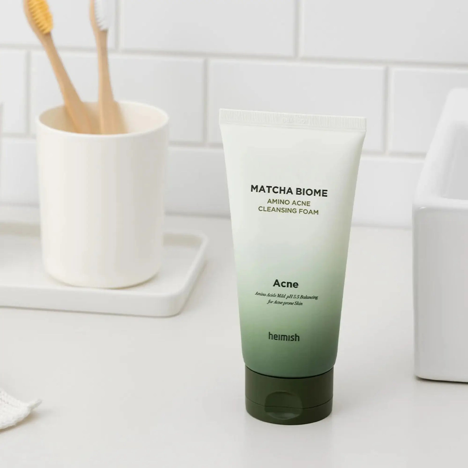 Heimish Matcha Biome Amino Acne Cleansing Foam 150g, espuma de limpeza facial coreana que remove oleosidade e impurezas sem ressecar, frasco em pé junto a lavatório branco sobre fundo branco, cosmética coreana skincare k-beauty Portugal.