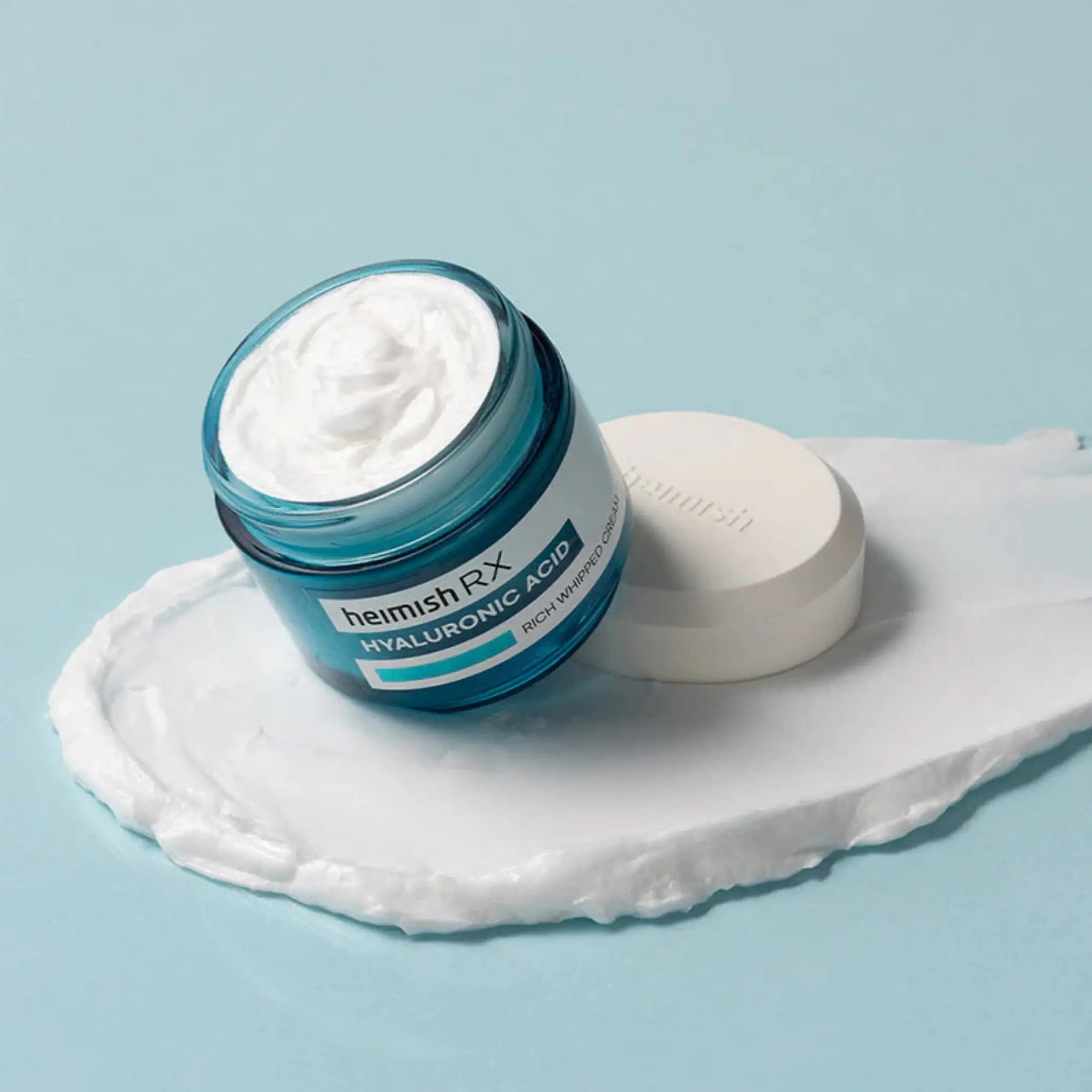 RX Hyaluronic Acid Rich Whipped Cream da Heimish com tampa ao lado em fundo azul