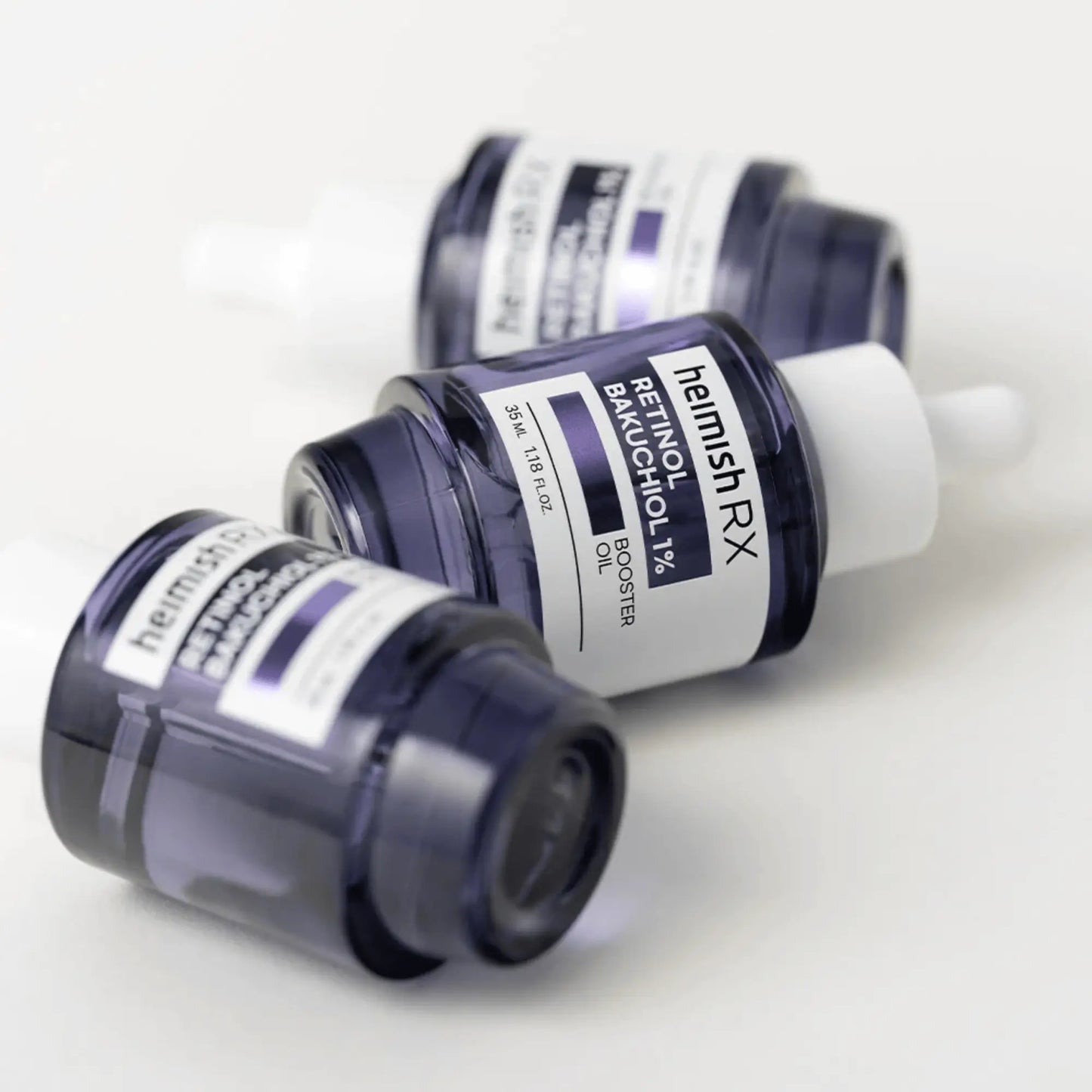 Heimish RX Retinol Bakuchiol Booster Oil 35ml, óleo facial coreano nutritivo com retinol e bakuchiol, reforça a regeneração e suaviza rugas, dois frascos deitados sobre fundo lilás claro, cosmética coreana skincare k-beauty Portugal.