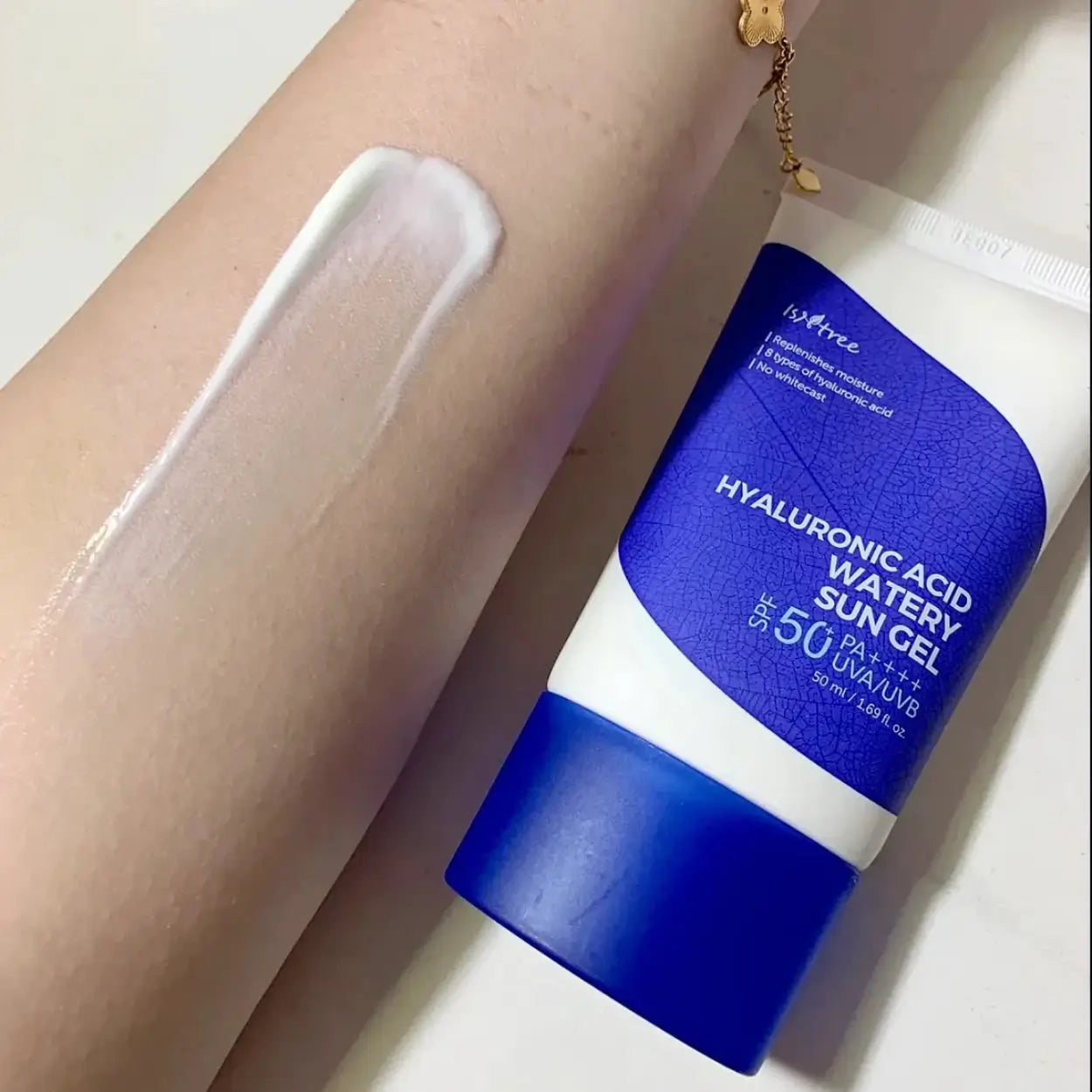 Isntree Hyaluronic Acid Watery Sun Gel – textura cremosa do protetor solar com ácido hialurónico aplicada no braço, mostrando a sua fórmula leve e sem acabamento esbranquiçado, ideal para pele seca e sensível, cosmética coreana e skincare k-beauty Portugal