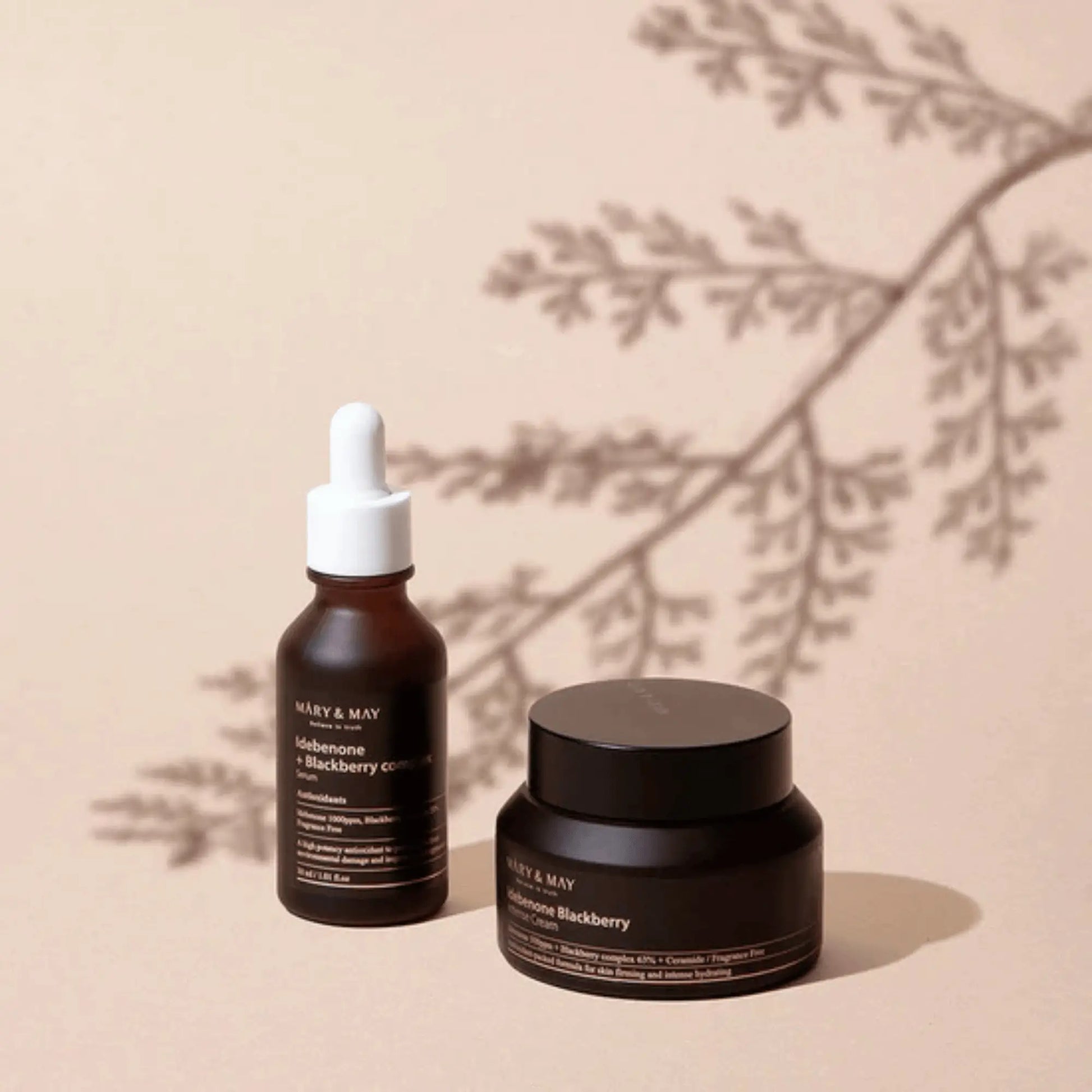 Mary & May Idebenone + Blackberry Complex Intensive Total Care Cream 70g, creme facial coreano antioxidante com idebenona e amora-preta, combina com o sérum da mesma linha para maior eficácia, frasco e sérum lado a lado com sombra de folha projetada, cosmética coreana skincare k-beauty Portugal.