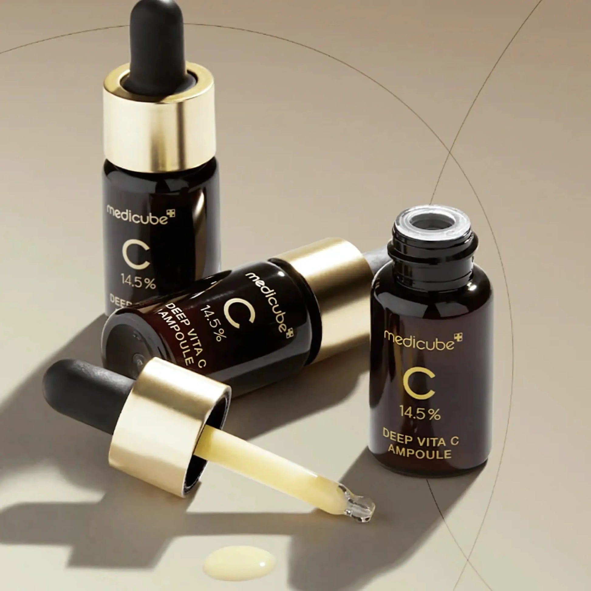 Medicube Deep Vita C Ampoule 2.0 – dois frascos sobre fundo bege com reflexo dourado, reforçando a ação antioxidante e iluminadora desta ampola coreana de alta eficácia