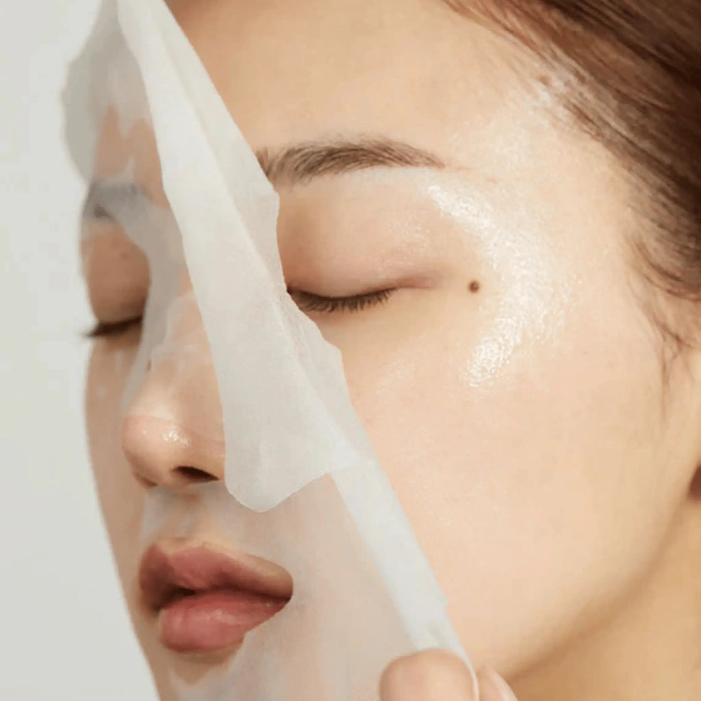 Super Cica Calming Mask da Medicube modelo a retirar sheet mask do rosto em close-up