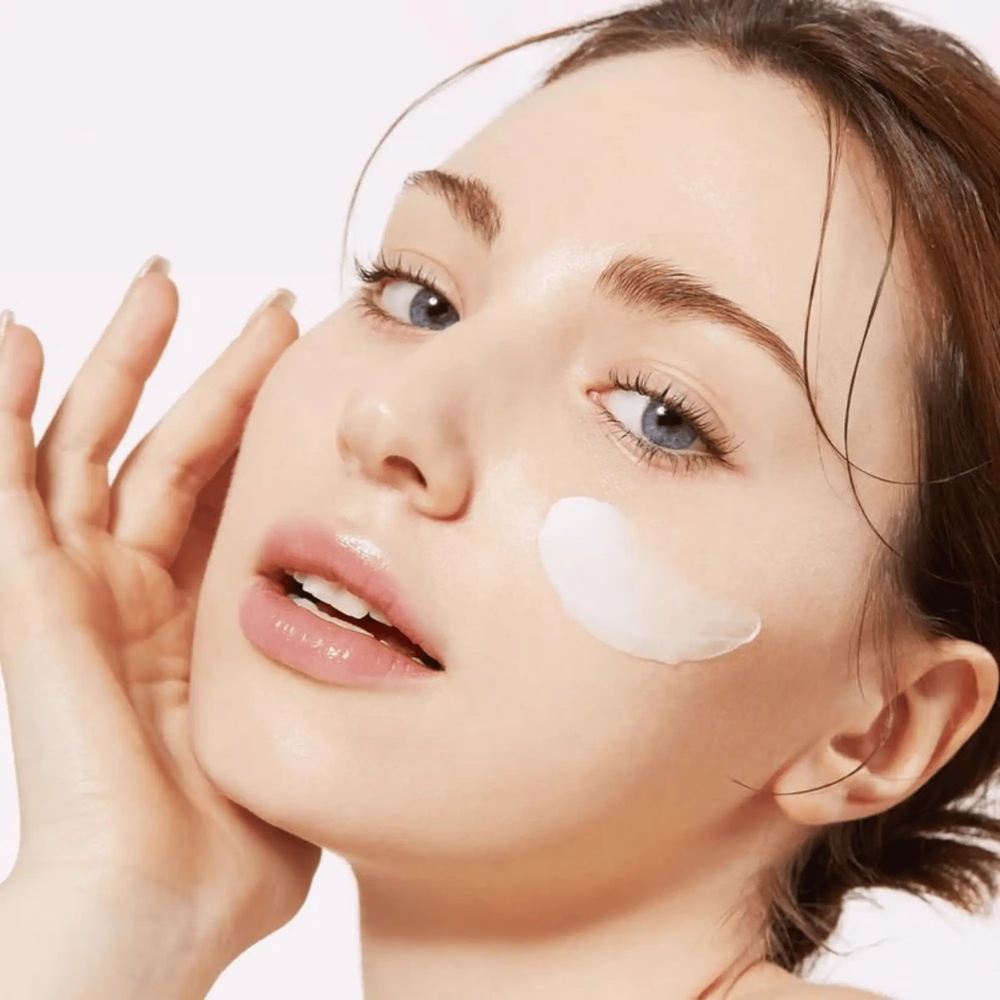 Medicube Triple Collagen Cream 4.0 50ml, creme facial coreano com colagénio triplo e peptídeos que hidratam em profundidade e suavizam linhas finas, close-up da modelo a espalhar o creme na bochecha, cosmética coreana skincare k-beauty Portugal.