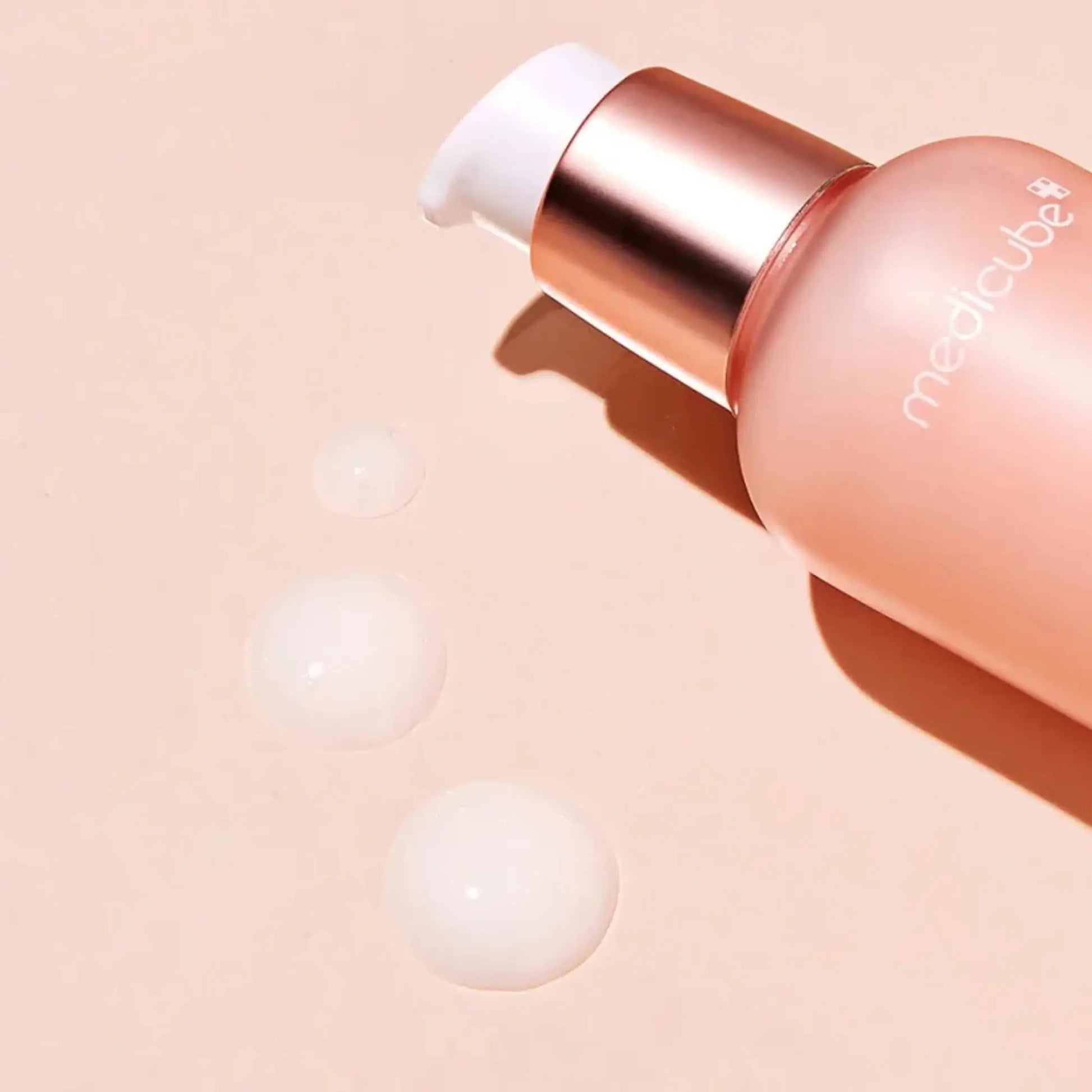Medicube Triple Collagen Cream 4.0 50ml, creme coreano anti-envelhecimento de textura rica com colagénio triplo para elasticidade e hidratação, frasco deitado com tampa aberta e gotas de creme ao lado sobre fundo bege claro, cosmética coreana skincare k-beauty Portugal.