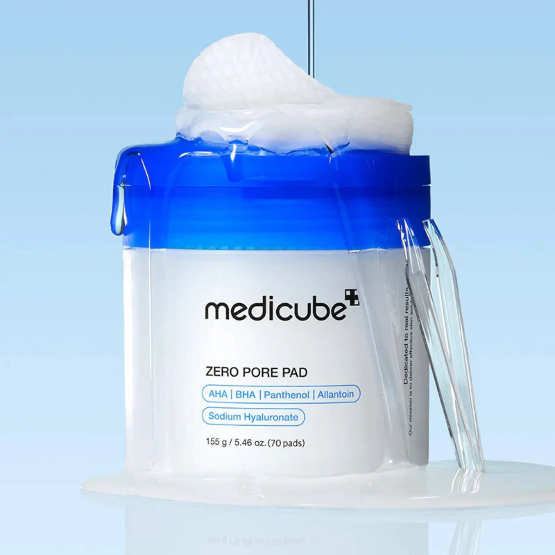 Medicube Zero Pore Pad 2.0 (70pcs), exfoliante facial coreano em discos com ácidos AHA, BHA e PHA, ajuda a controlar oleosidade e suavizar textura irregular, disco a ser levantado com líquido a escorrer de frasco com tampa azul, fundo azul, cosmética coreana skincare k-beauty Portugal.
