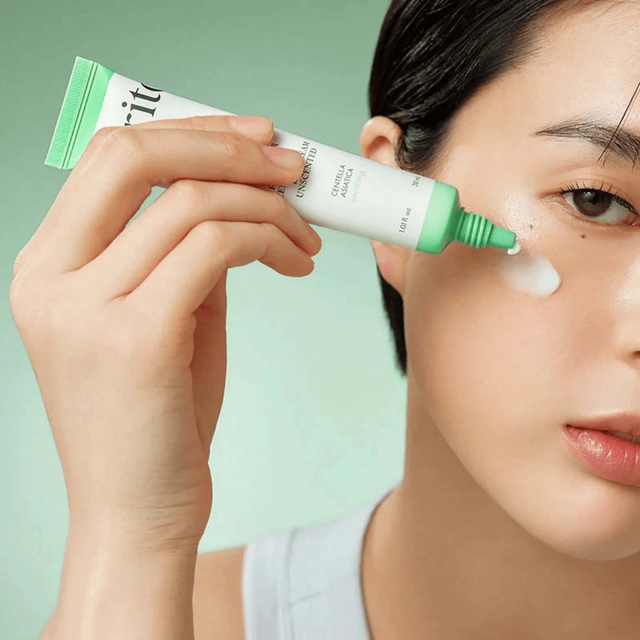 Wonder Releaf Centella Eye Cream Unscented da Purito Seoul aplicação no rosto com tubo junto à bochecha