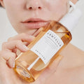 Madagascar Centella Light Cleansing Oil da Skin1004 modelo segura frasco âmbar junto ao rosto em close-up