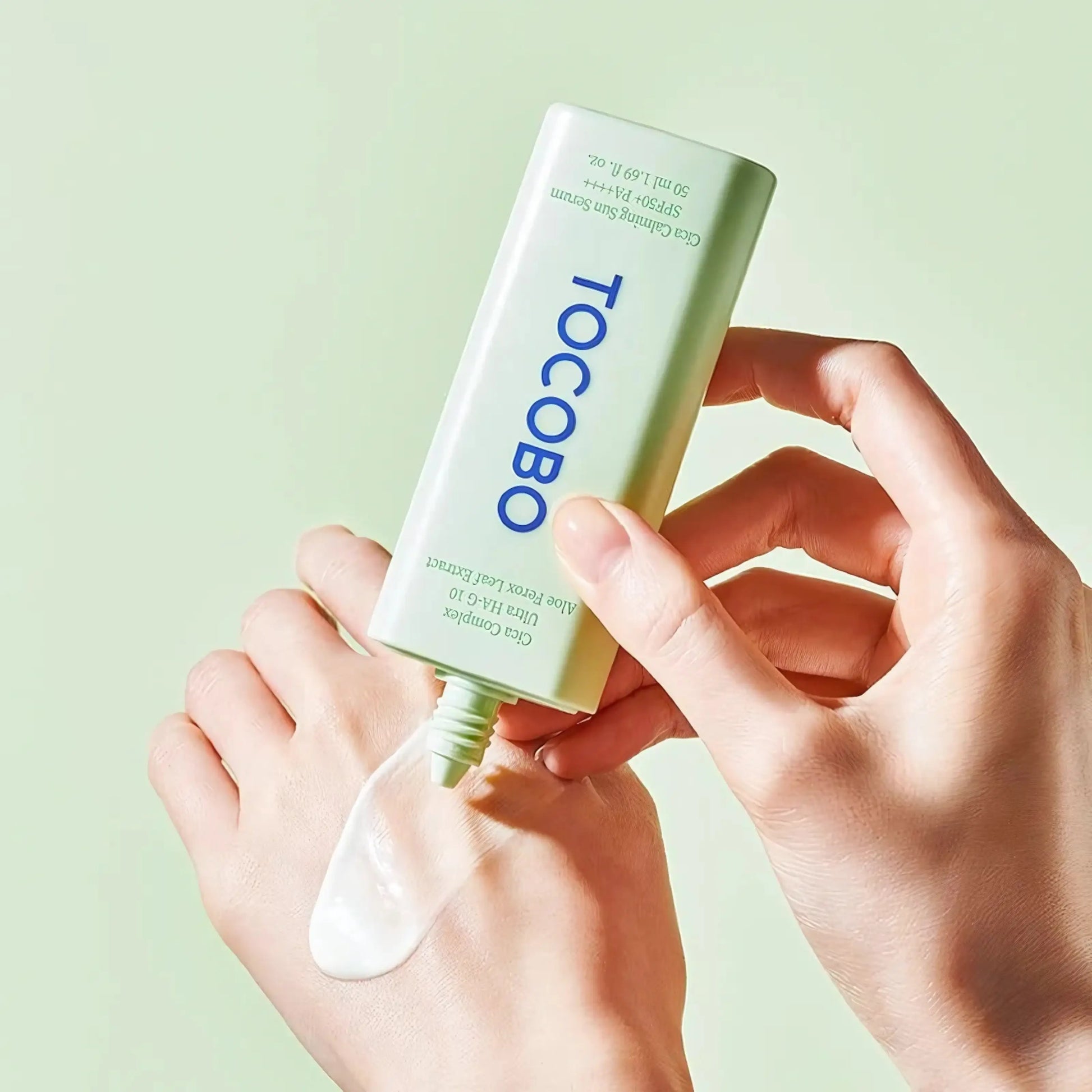 TOCOBO Cica Calming Sun Serum – embalagem inclinada sobre fundo azul com reflexo, sugerindo textura fluida e efeito refrescante na pele, ideal para uso diário

