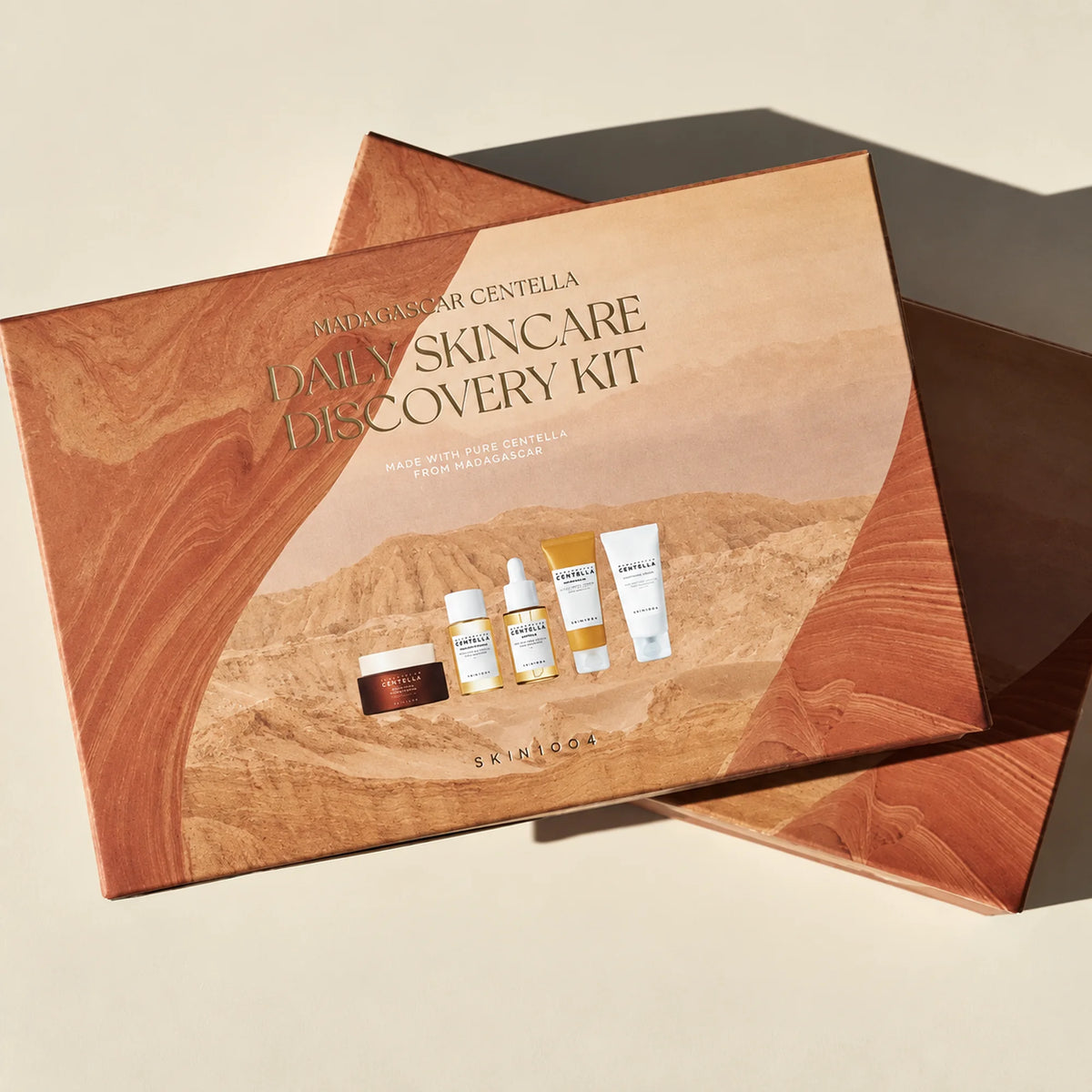 Duas caixas do SKIN1004 Madagascar Centella Daily Skincare Discovery Kit sobre fundo bege.