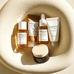 Cinco produtos do kit de viagem SKIN1004 Madagascar Centella, dispostos num tabuleiro em tons de creme.
